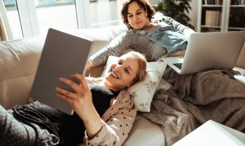 Two women looking at tablet on a couch